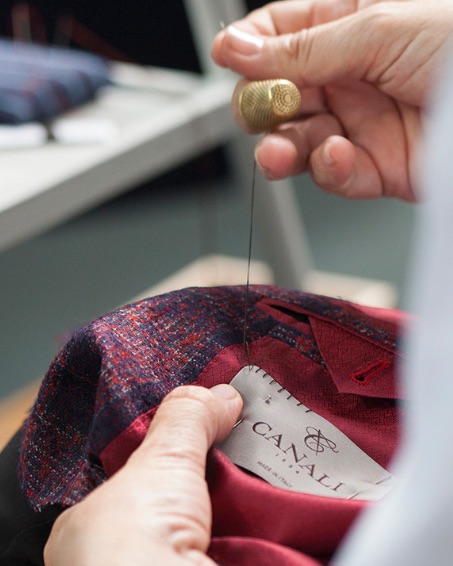 A craftsperson stitches a Canali suit.