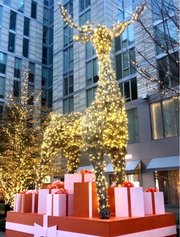 A 25-ft tall sculpture of a reindeer standing atop orange and yellow presents, all covered in twinkling lights.