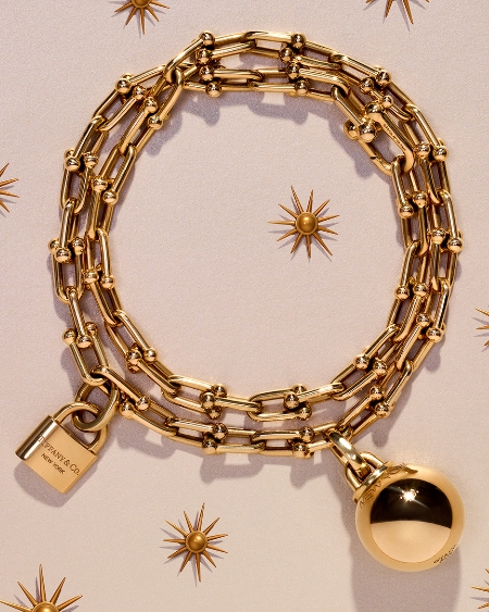 A gold bracelet with a lock and ornament hanging from it