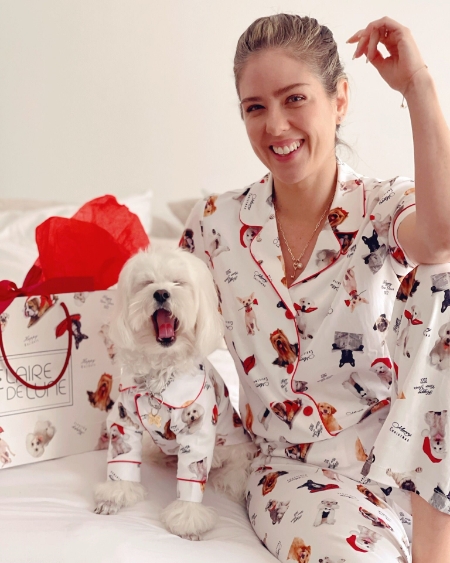 A woman and a dog wearing matching dog-printed pajamas