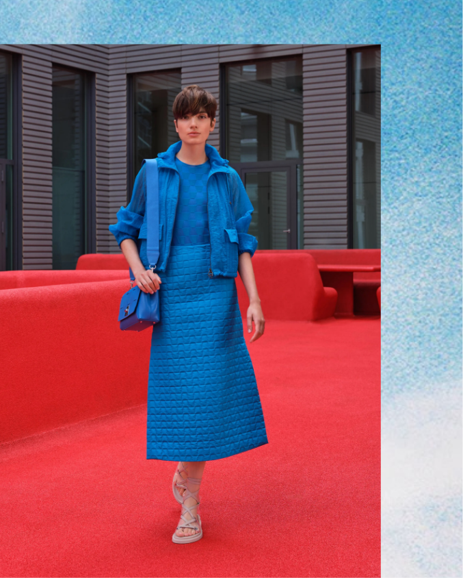 Woman wearing blue dress and jacket standing on red carpet installation