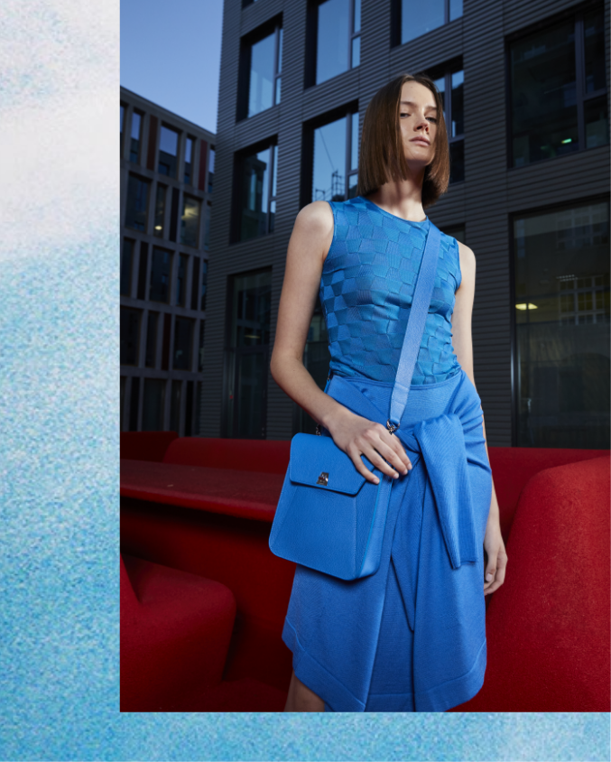 Woman wearing full blue outfit from AKRIS standing on red carpet installation