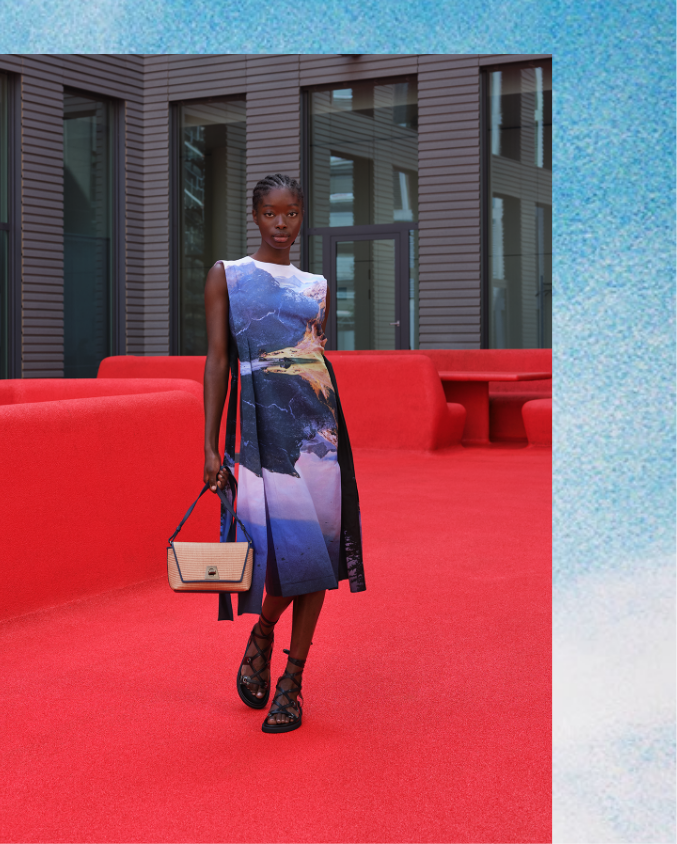 Woman wearing photo-printed dress from AKRIS standing on red carpet installation