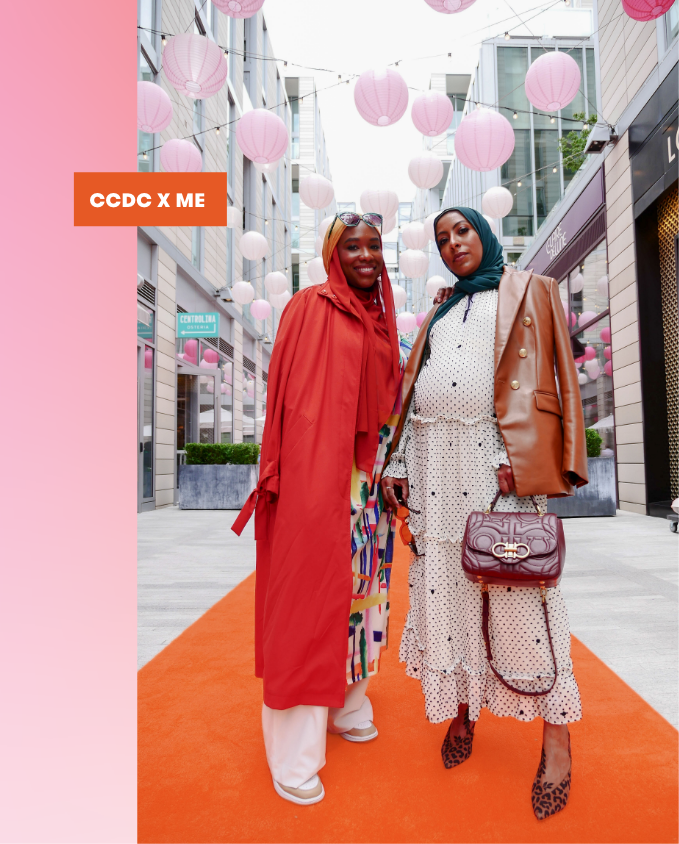 Two friends standing together on orange carpet and Pink Lanterns in the background.