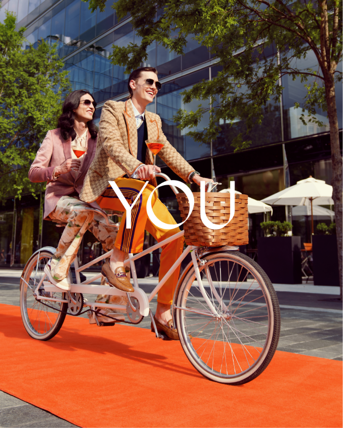 Two men riding a bike in front of Gucci and Tatte in CityCenterDC